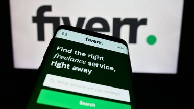 Stuttgart, Almanya - 02-11-2024: Serbest platform şirketi Fiverr International Ltd. 'nin web sitesiyle birlikte iş logosu önünde cep telefonu. Telefon ekranının sol üst kısmına odaklan.