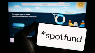 Stuttgart, Almanya - 02-12-2024: ABD 'li kitle fonlama şirketi Spotfon Technologies Inc.' in logosuna sahip akıllı telefon sahibi kişi web sitesinin önünde. Telefon ekranına odaklan.