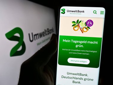 Stuttgart, Almanya - 02-12-2024: Alman finans hizmetleri şirketi Umweltbank AG 'nin web sayfası ile logo önünde akıllı telefon tutan kişi. Telefon ekranının merkezine odaklan.