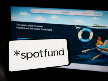 Stuttgart, Almanya - 02-12-2024: ABD 'li kitle fonlama şirketi Spotfund Technologies Inc.' in logosuyla cep telefonu sahibi kişi iş sayfasının önünde. Telefon ekranına odaklan.
