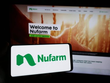 Stuttgart, Almanya - 02-12-2024: Avustralyalı tarım kimya şirketi Nufarm Limited 'in logosuna sahip akıllı telefon sahibi kişi web sitesinin önünde. Telefon ekranına odaklan.