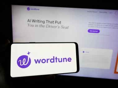 Stuttgart, Almanya - 02-12-2024: Web sayfası önünde üzerinde yapay zeka arkadaşı Wordtune (AI21 Labs) logosu bulunan cep telefonu sahibi kişi. Telefon ekranına odaklan.