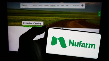 Stuttgart, Almanya - 02-12-2024: Avustralyalı tarım kimya şirketi Nufarm Limited 'in logosunu taşıyan cep telefonu sahibi kişi iş sayfasının önünde. Telefon ekranına odaklan.