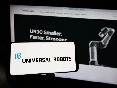 Stuttgart, Almanya - 02-12-2024: Danimarkalı kobot şirketi Universal Robots AS 'in logosuyla cep telefonu tutan kişi iş sayfasının önünde. Telefon ekranına odaklan.