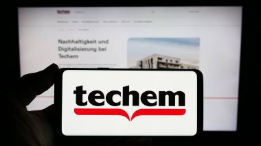 Stuttgart, Almanya - 02-13-2024: Alman enerji hizmetleri şirketi Techem GmbH 'nin logosuna sahip akıllı telefon sahibi kişi web sitesinin önünde. Telefon ekranına odaklan.