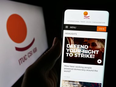 Stuttgart, Almanya - 02-13-2024: Logolu Uluslararası Ticaret Birliği Konfederasyonu (ITUC) web sayfası ile akıllı telefon sahibi kişi. Telefon ekranının merkezine odaklan.