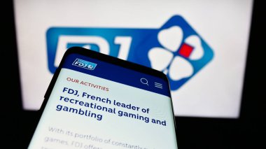 Stuttgart, Almanya - 02-13-2024: Fransız piyango şirketi Francaise des Jeux 'un (FDJ) internet sitesi ile birlikte iş logosu önünde akıllı telefon. Telefon ekranının sol üst kısmına odaklan.