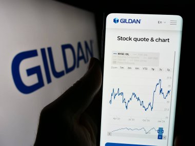 Stuttgart, Almanya - 02-13-2024: Kanadalı giyim şirketi Gildan Activewear Inc. 'in logo önünde web sayfası ile akıllı telefon tutan kişi. Telefon ekranının merkezine odaklan.
