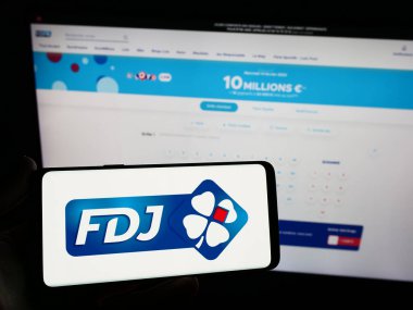 Stuttgart, Almanya - 02-13-2024: Fransız piyango şirketi Francaise des Jeux 'un logosunu taşıyan cep telefonu sahibi şirket web sitesinin önünde. Telefon ekranına odaklan.