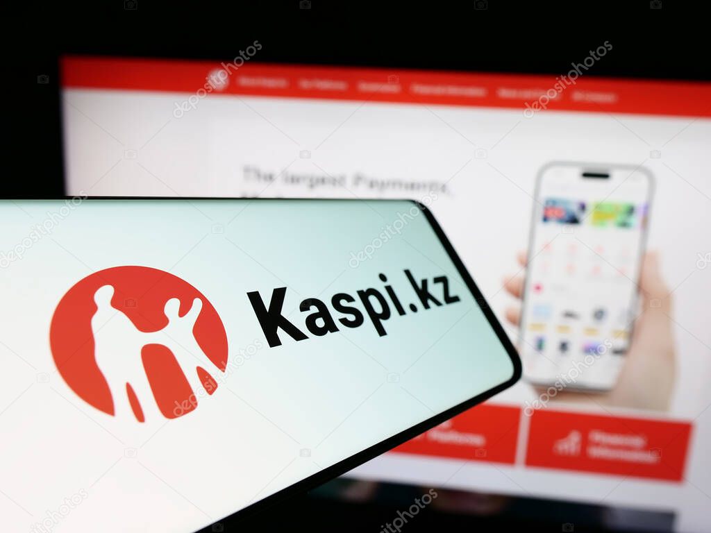 Stuttgart, Germany - 02-13-2024: Mobile phone with logo of Kazakh financial services company Kaspi.kz in front of business website. Focus on center-left of phone display.