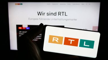 Stuttgart, Almanya - 02-13-2024: İnternet sitesi önünde üzerinde medya ve televizyon şirketi RTL Group S.A. logosu bulunan kişi. Telefon ekranına odaklan.