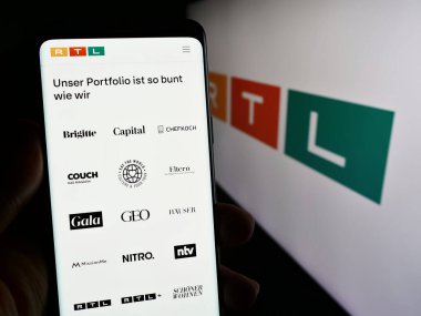 Stuttgart, Almanya - 02-13-2024: Cep telefonunda medya ve televizyon şirketi RTL Group S.A. 'nın web sayfası bulunan kişi logonun önünde. Telefon ekranının merkezine odaklan.