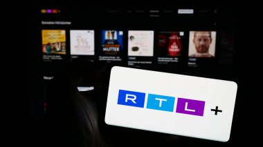Stuttgart, Almanya - 02-13-2024: Alman eğlence platformu RTL artı iş sayfasının önünde logosu olan cep telefonu sahibi kişi. Telefon ekranına odaklan.