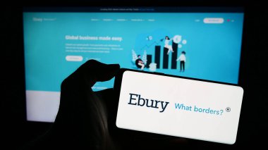 Stuttgart, Almanya - 02-13-2024: İngiliz finans şirketi Ebury Partners UK Ltd. 'nin logosuyla cep telefonu tutan kişi iş sayfasının önünde. Telefon ekranına odaklan.