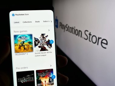 Stuttgart, Almanya - 02-14-2024: Oyun mağazası PlayStation Store 'un (PS Store) internet sayfası olan akıllı telefonu logonun önünde tutan kişi. Telefon ekranının merkezine odaklan.