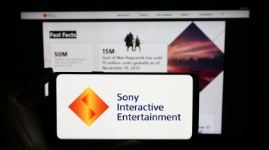 Stuttgart, Almanya - 02-14-2024: Web sayfası önünde Amerikan video oyunu şirketi Sony Interactive Entertainment LLC 'nin logosuyla cep telefonu tutan kişi. Telefon ekranına odaklan.