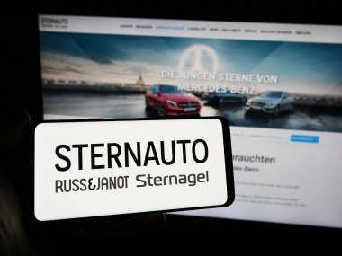 Stuttgart, Almanya - 02-15-2024: Alman otomobil dağıtım şirketi Stern Auto Holding GmbH 'nin logosunu taşıyan cep telefonu sahibi iş sayfası önünde. Telefon ekranına odaklan.