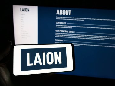Stuttgart, Almanya - 02-15-2024: Web sitesi önünde üzerinde büyük ölçekli Yapay Zeka Açık Ağı (LAION) logosu bulunan kişi. Telefon ekranına odaklan.