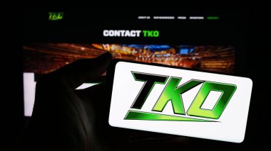 Stuttgart, Germany - 02-15-2024: Person holding cellphone with logo of US media company TKO Group Holdings Inc. in front of business webpage. Focus on phone display. clipart