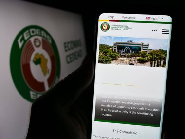 Stuttgart, Almanya - 02-15-2024: Batı Afrika Eyaletleri Ekonomik Topluluğu (ECOWas) web sitesi logosu önünde cep telefonu tutan kişi. Telefon ekranının merkezine odaklan.