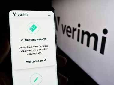 Stuttgart, Almanya - 02-15-2024: Alman kimlik yönetim şirketi Verimi GmbH 'nin internet sayfası ile logo önünde cep telefonu tutan kişi. Telefon ekranının merkezine odaklan.