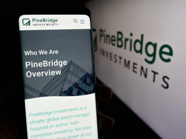 Stuttgart, Almanya - 02-15-2024: Logo önünde ABD 'li yatırım şirketi PineBridge Investments LLC' nin web sayfası ile akıllı telefon tutan kişi. Telefon ekranının merkezine odaklan.