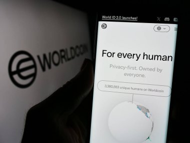Stuttgart, Almanya - 02-15-2024: Şifreleme projesi Worldcoin (İnsanlık İçin Araçlar) web sayfası logosu önünde cep telefonu tutan kişi. Telefon ekranının merkezine odaklan.