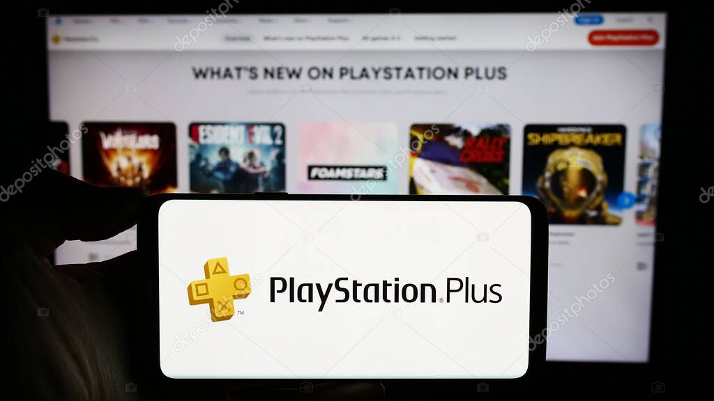 Stuttgart, Germany - 02-14-2024: Person holding cellphone with logo of subscription service PlayStation Plus (PS Plus) in front of business webpage. Focus on phone display.