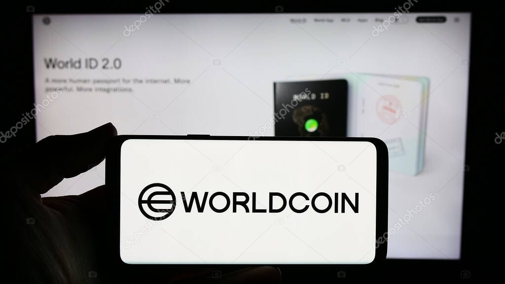Stuttgart, Germany - 02-15-2024: Person holding smartphone with logo of cryptocurrency project Worldcoin (Tools for Humanity) in front of website. Focus on phone display.