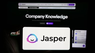 Stuttgart, Almanya - 02-16-2024: ABD 'li yapay zeka şirketi Jasper AI Inc.' in logosuyla cep telefonu sahibi kişi iş sayfasının önünde. Telefon ekranına odaklan.