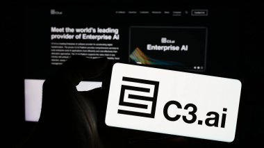 Stuttgart, Almanya - 02-19-2024: ABD 'li yapay zeka şirketi C3.ai Inc.' in logosuyla cep telefonu sahibi kişi iş sayfasının önünde. Telefon ekranına odaklan.