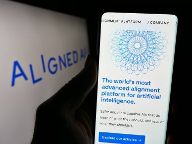 Stuttgart, Almanya - 02-19-2024: İngiliz yapay zeka şirketi Aligned Al 'in web sitesi ile logo önünde cep telefonu tutan kişi. Telefon ekranının merkezine odaklan.