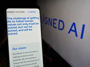 Stuttgart, Almanya - 02-19-2024: İngiliz yapay zeka şirketi Aligned AI 'ın logo ile birlikte web sayfası ile cep telefonu tutan kişi. Telefon ekranının merkezine odaklan.