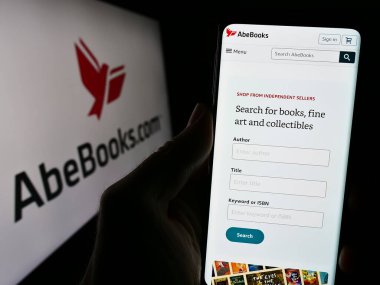 Stuttgart, Almanya - 02-19-2024: Kanadalı e-ticaret şirketi AbeBooks Inc. 'in internet sayfası ile akıllı telefon sahibi kişi iş logosu önünde. Telefon ekranının merkezine odaklan.