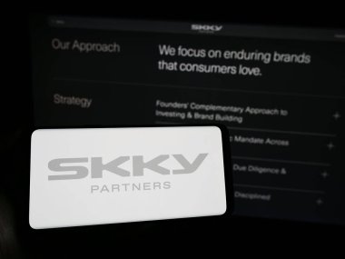 Stuttgart, Almanya - 02-19-2024: Amerikan yatırım şirketi SKY Partners LP 'nin logosunu taşıyan cep telefonu sahibi kişi iş sayfasının önünde. Telefon ekranına odaklan.