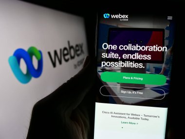 Stuttgart, Almanya - 02-19-2024: ABD birleşik iletişim şirketi Webex 'in web sayfası ile cep telefonu tutan kişi logo önünde Cisco. Telefon ekranının merkezine odaklan.