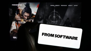 Stuttgart, Germany - 02-19-2024: Person holding cellphone with logo of Japanese video games company FromSoftware Inc. in front of business webpage. Focus on phone display. clipart