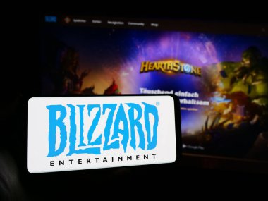 Stuttgart, Almanya - 02-21-2024: Web sayfasının önünde Amerikan video oyunu şirketi Blizzard Entertainment Inc. 'in logosuyla cep telefonu tutan kişi. Telefon ekranına odaklan.