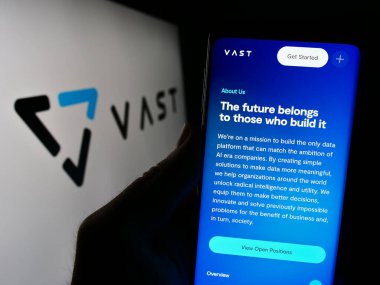 Stuttgart, Almanya - 02-21-2024: ABD 'li yapay zeka şirketi VAST Data Inc.' in web sayfası ile logo önünde cep telefonu tutan kişi. Telefon ekranının merkezine odaklan.