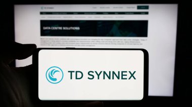 Stuttgart, Almanya - 02-21-2024: ABD 'li bilişim dağıtım şirketi TD SyNNEX Corporation' ın logosuyla cep telefonu tutan kişi iş sayfası önünde. Telefon ekranına odaklan.