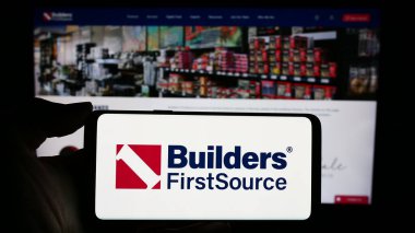 Stuttgart, Almanya - 02-22-2024: İnternet sitesi önünde ABD 'li inşaat malzemeleri şirketi Builders First Source Inc.' in logosuna sahip kişi. Telefon ekranına odaklan.