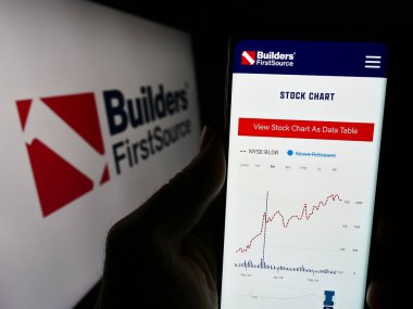 Stuttgart, Almanya - 02-22-2024: ABD 'li inşaat malzemeleri şirketi Builders First Source Inc.' in logolu web sayfası ile cep telefonu tutan kişi. Telefon ekranının merkezine odaklan.