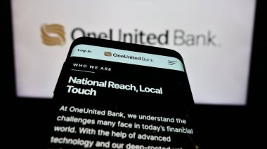 Stuttgart, Almanya - 02-22-2024: ABD 'li finans hizmetleri şirketi OneUnited Bank' ın web sitesiyle birlikte iş logosu önünde cep telefonu. Telefon ekranının sol üst kısmına odaklan.