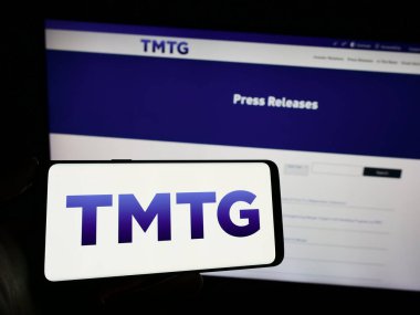Stuttgart, Almanya - 02-22-2024: İnternet sayfası önünde Amerikan Trump Media Technology Group (TMTG) logosunun bulunduğu cep telefonu sahibi kişi. Telefon ekranına odaklan.