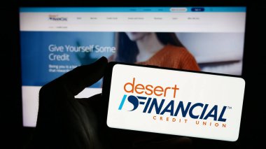 Stuttgart, Almanya - 02-22-2024: İnternet sitesi önünde ABD 'li finans hizmetleri şirketi Desert Financial Credit Union' un logosuna sahip kişi. Telefon ekranına odaklan.