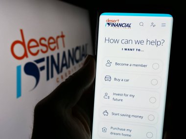 Stuttgart, Almanya - 02-22-2024: ABD 'li finans hizmetleri şirketi Desert Financial Credit Union' un logolu web sayfası ile akıllı telefon sahibi kişi. Telefon ekranının merkezine odaklan.