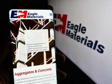 Stuttgart, Almanya - 02-23-2024: ABD 'li inşaat şirketi Eagle Materials Inc.' in web sayfası ile logo önünde cep telefonu tutan kişi. Telefon ekranının merkezine odaklan.