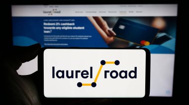 Stuttgart, Germany - 02-23-2024: Person holding cellphone with logo of US banking platform company Laurel Road (KeyBank) in front of business webpage. Focus on phone display. clipart