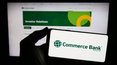 Stuttgart, Almanya - 02-23-2024: İnternet sitesi önünde ABD 'li bankacılık şirketi Commerce Bancshare Inc.' in logosuna sahip kişi. Telefon ekranına odaklan.