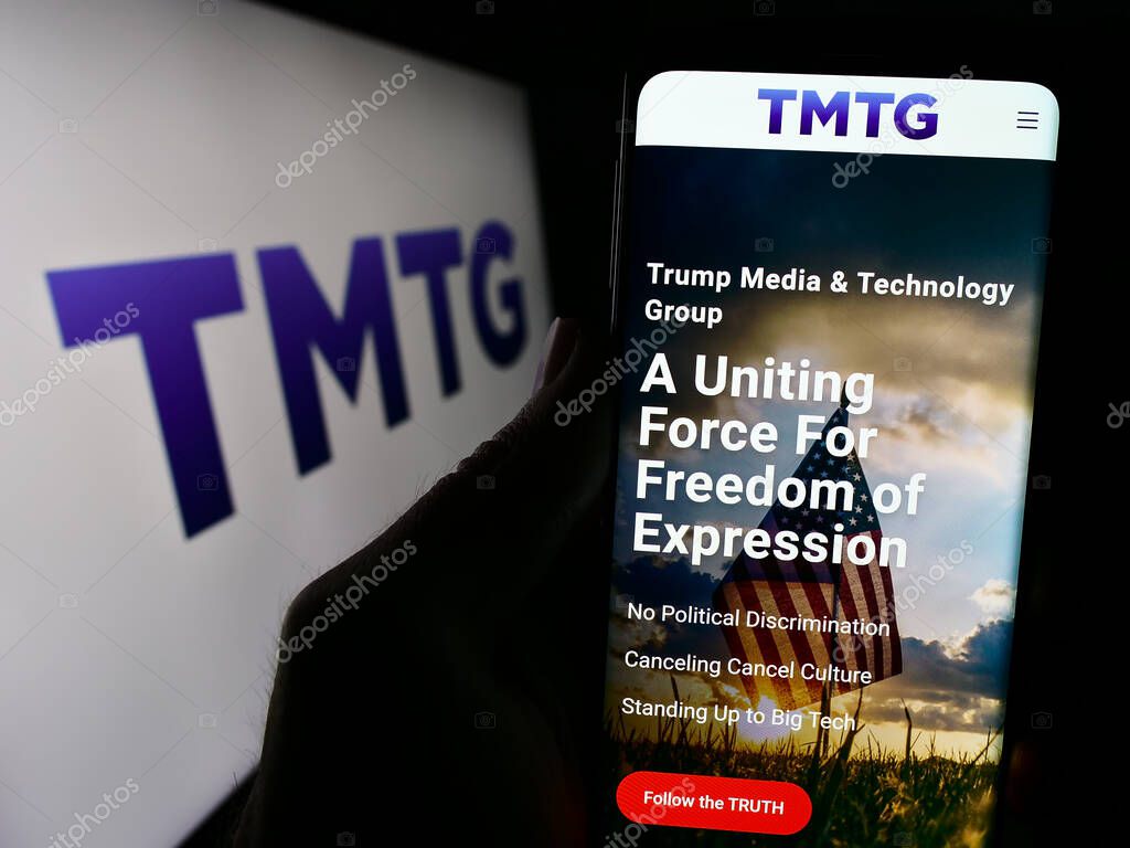 Stuttgart, Germany - 02-22-2024: Person holding cellphone with webpage of US company Trump Media Technology Group (TMTG) in front of logo. Focus on center of phone display.